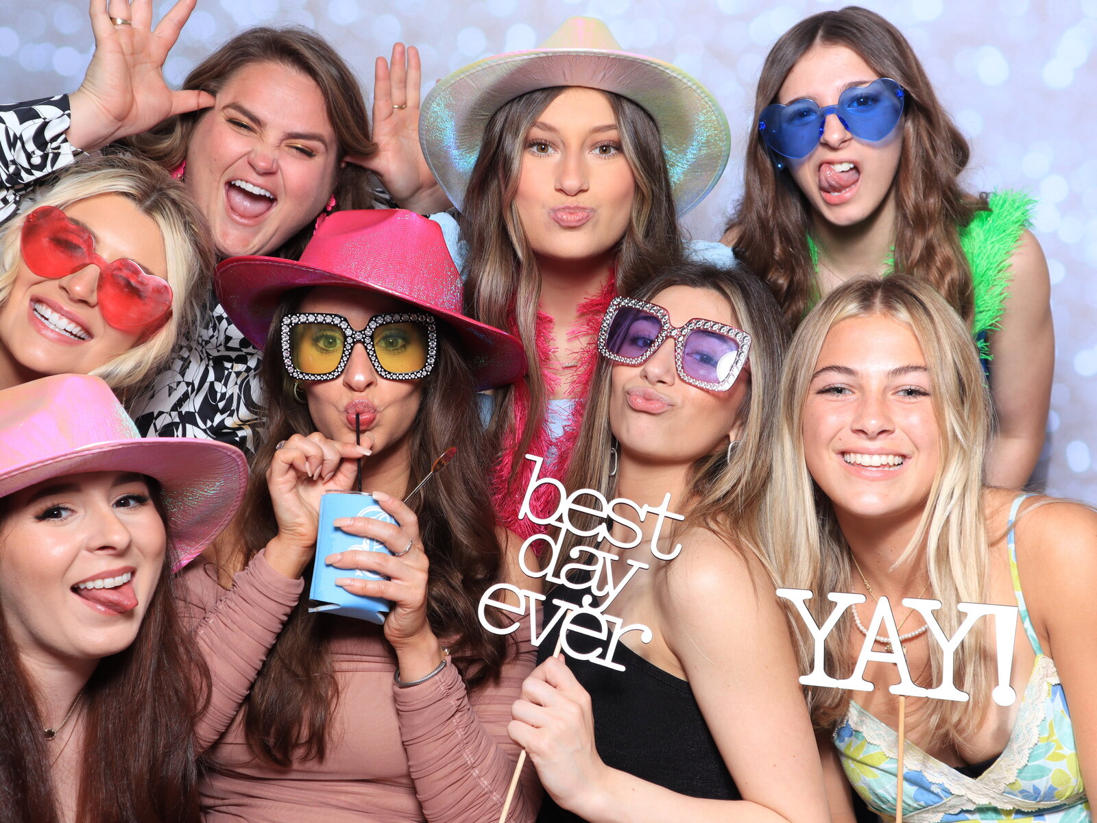 Friends holding 'best day ever' signs in the booth