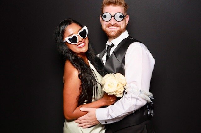 Couple in white sunglasses posing in the booth