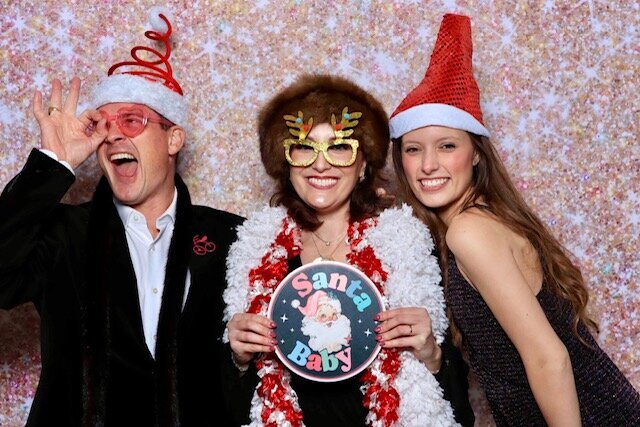 Holiday party guests with Santa props in the booth