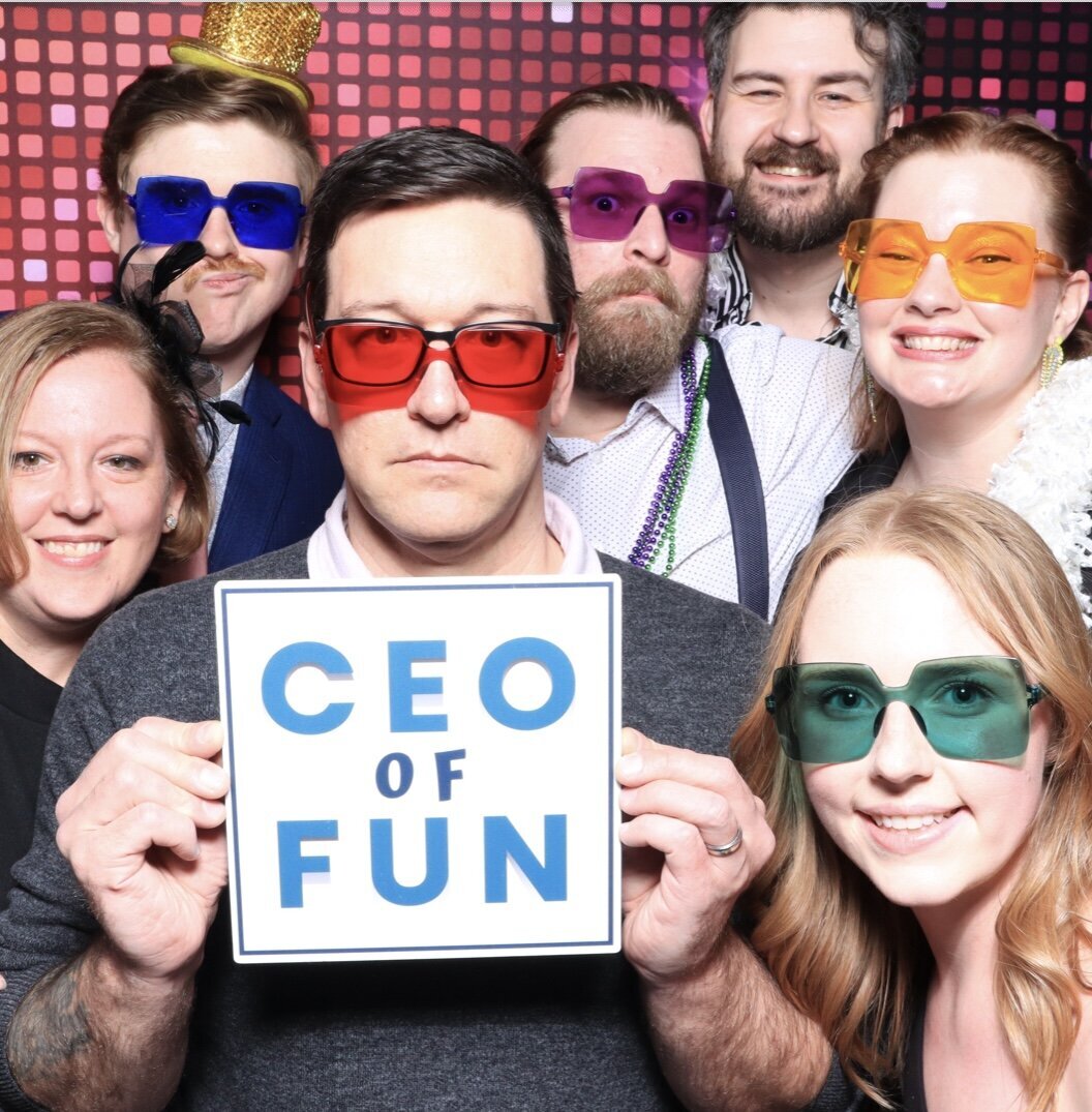 Corporate team posing with a 'CEO of Fun' sign