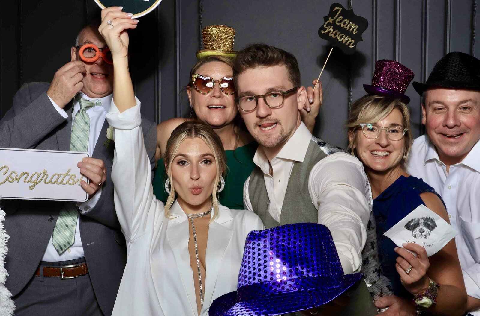 Wedding party crowding into the photo booth with props